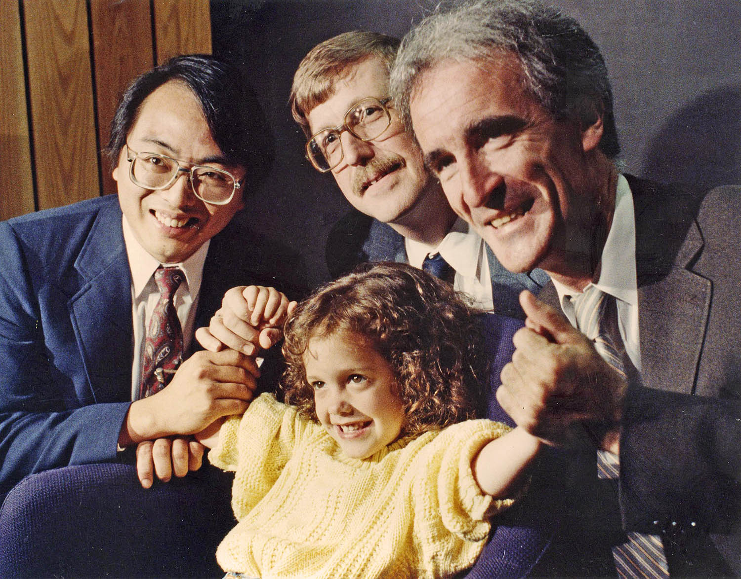 Une photo de 1989 d'une jeune fille atteinte de mucoviscidose posant avec des scientifiques de l'époque.